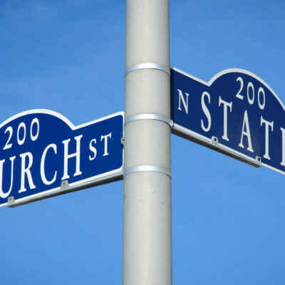 Two street signs at an intersection on a pole reading Church St on one and State St on the other.