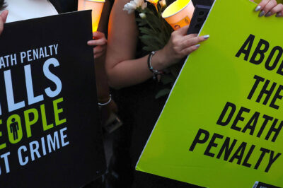 Two demonstrators hold signs that reads "THE DEATH PENALTY KILLS PEOPLE NOT CRIME" and "ABOLISH THE DEATH PENALTY."