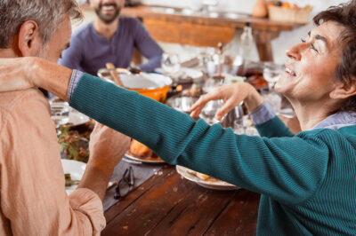 Group of diverse people together around food at dinning table, talking and gathering for Holiday