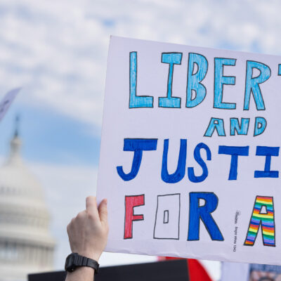A demonstrator holds up a sign that reads, "LIBERTY AND JUSTICE FOR ALL" at the No Kings National Day of Action protest near the U.S. Capitol building in Washington, D.C., October 18, 2025.