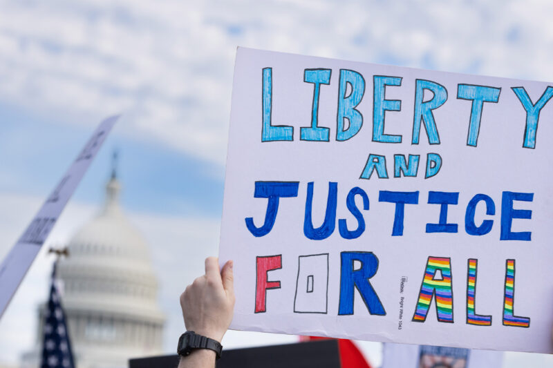 A demonstrator holds up a sign that reads, "LIBERTY AND JUSTICE FOR ALL" at the No Kings National Day of Action protest near the U.S. Capitol building in Washington, D.C., October 18, 2025.