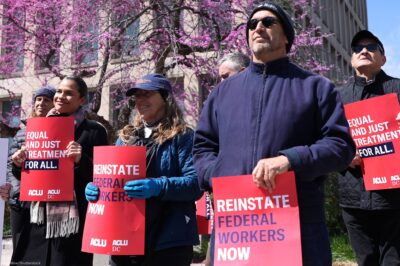 Demonstrators hold signs from ACLU & ACLU DC that read" REINSTATE FEDERAL WORKERS NOW" and "EQUAL AND JUST TREATMENT FOR ALL" as they protest in support of Federal Workers at the Office of Personnel Management in Washington, DC.