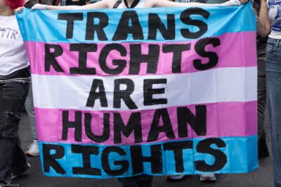 Trans Rights, speakers, protesters, and supporters denounce the Trump Administration's persistent attacks on the transgender community. by carrying a huge sign reading" TRANS RIGHTS ARE HUMAN RIGHTS".