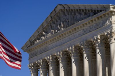 A half-lowered US flag waves in front of the US Supreme Court.